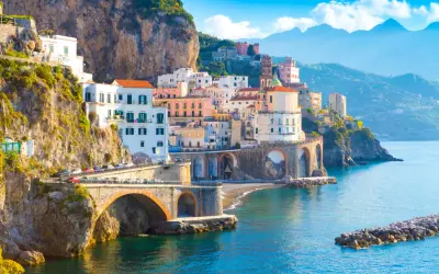 Widok na wybrzeże Amalfi z kolorowymi domami na klifie i mostem. Nawet przy takich widokach, objawy lęku przed ekspozycją na szlakach wybrzeża Amalfi a wyspa Capri mogą być odczuwalne.