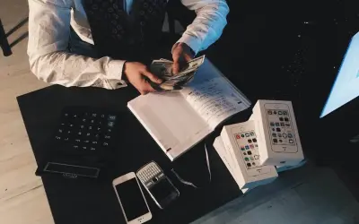 Mężczyzna liczy pieniądze, obok leżą telefony i kalkulator. To może być pomocne, jak udowodnić pochodzenie pieniędzy.