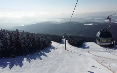 Widok z kolejki linowej na ośnieżony stok narciarski. Sprawdź jańskie łaźnie ski cennik i zaplanuj swój wyjazd!