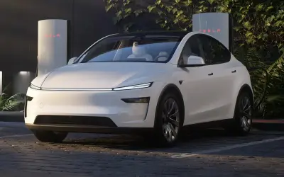 Biała Tesla zaparkowana przy ładowarce Supercharger.