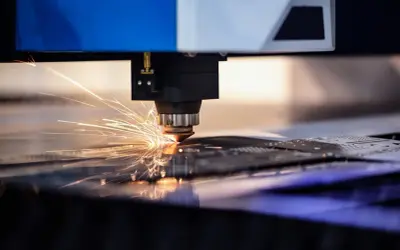Precyzyjne cięcie aluminium przez laser, iskry rozbłyskują podczas pracy maszyny.