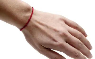Czerwona nitka na nadgarstku symbolizuje ochronę i szczęście. To amulet, który ma odpędzać złe moce i przyciągać pozytywną energię.