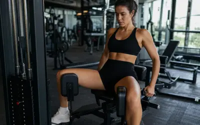 Donna si allena in palestra per dimagrire l'interno coscia con una macchina specifica.
