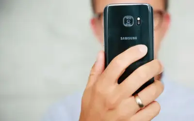 Osoba trzyma czarny telefon Samsung, pokazując tył z aparatem. Dowiedz się, jak poprawić jakość aparatu w telefonie Samsung, aby robić lepsze zdjęcia.