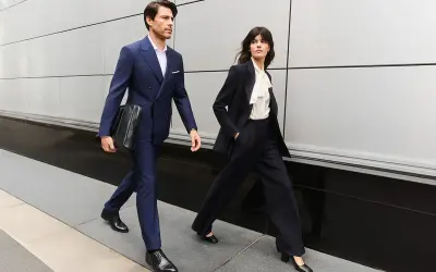 Para idąca ulicą w eleganckich, granatowych garniturach, przykład biznesowego stylu formalnego.