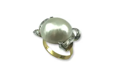 Anillo de oro con un gran anillo perla japonesa central, rodeado de pequeños diamantes incrustados en filigrana de plata.