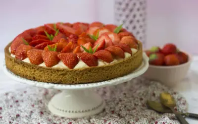 Tarte aux fraises sablé breton, garnie de crème pâtissière et de fraises fraîches, décorée de feuilles de menthe.