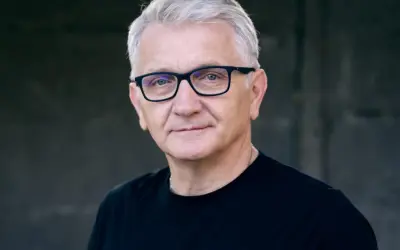 Portret Dariusza Kowalskiego, aktora, w okularach i czarnej koszulce.