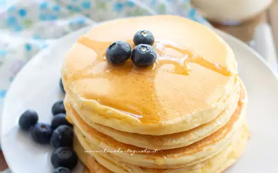 Pancakes soffici con albumi, guarniti con mirtilli freschi e sciroppo d'acero.