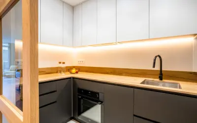 Cocinas negras y madera, con encimera de madera clara, armarios superiores blancos y detalles modernos.