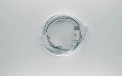 Biały kabel USB C, zwinięty w okrąg, z widocznymi złączami. Opis żył tego kabla jest kluczowy dla jego funkcjonalności.