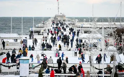 Sopot atrakcje zimą: lodowisko na molo, tłumy ludzi w ciepłych ubraniach, morze w tle.
