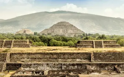 Majestätische Maya-Ruinen erheben sich vor einer sanften Bergkulisse. Alte Steinstrukturen und Pyramiden zeugen von einer vergangenen Zivilisation.