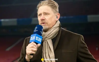 Antoni Schmeichel, z mikrofonem CBS Sports i szalikiem, komentuje mecz Ligi Mistrzów.