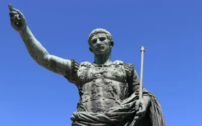 Bronzestatue eines römischen Kaisers, der mit erhobener Hand und Zepter auf den Betrachter blickt. Sie symbolisiert, wie wurde Rom regiert.