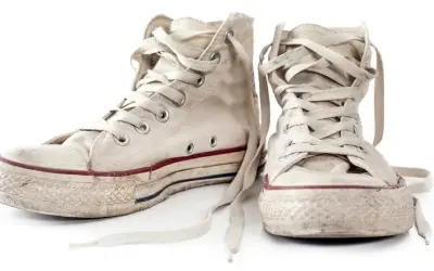 Zwei abgetragene, weiße Chucks mit Schnürsenkeln, bereit zum Chucks waschen.