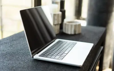 Nowy laptop czeka na pierwsze uruchomienie. Na blacie obok stoją ozdobne świeczniki.