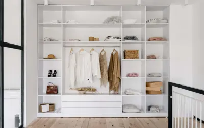 Idéal pour aménager un placard : étagères blanches remplies de vêtements, accessoires et boîtes.