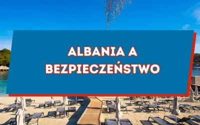 Piękna plaża w Albanii, gdzie słońce świeci, a leżaki czekają. Czy w Albanii jest bezpiecznie? Odpowiedź znajdziesz na niebieskim tle.