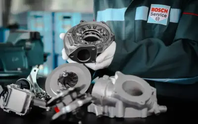Mechanik w rękawiczkach prezentuje części turbosprężarki. Dowiedz się, ile kosztuje regeneracja turbiny w Bosch Service.