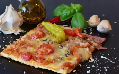 Pyszny kawałek pizzy z pomidorami i papryką, czosnkiem i bazylią. Zastanawiasz się, ile może leżeć pizza w lodówce?