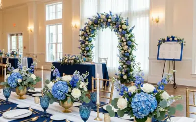 Elegancka dekoracja sali weselnej w odcieniach niebieskiego. Kwiatowe łuki i bukiety tworzą magiczną atmosferę.