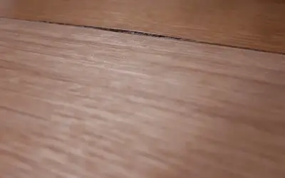Szczelina na blacie kuchennym wymaga naprawy. Widoczne drewniane słoje sugerują potrzebę renowacji.