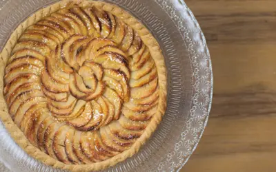 Tarte aux pommes recette : une tarte aux pommes dorée, disposée en spirale sur un plat en verre, prête à être dégustée.