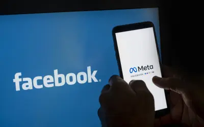 Chcesz wiedzieć, jak zablokować konto na Facebooku? Na ekranie telefonu widać logo Meta i Facebooka.