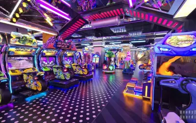 Kolorowy park rozrywki w Łodzi z maszynami do gier, w tym motocyklami i wyścigami.