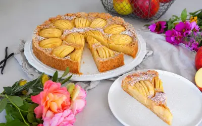 Ein sensationelles Apfeltarte-Rezept: goldbrauner Boden, saftige Äpfel, Puderzucker. Daneben eine Rose und Äpfel im Korb.