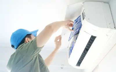 Un technicien nettoie le filtre d'une climatisation, une obligation pour le bailleur afin d'assurer le confort et la qualité de l'air.