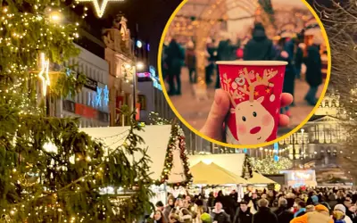 Ciepły kubek z reniferem na jarmarku bożonarodzeniowym w Pradze. Tłumy ludzi, choinki i świąteczne iluminacje tworzą magiczną atmosferę.