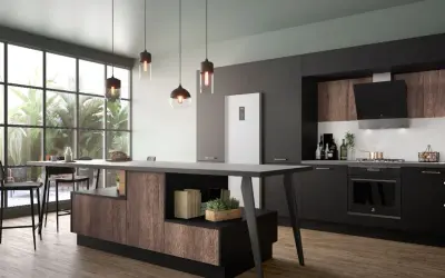 Cuisine fermée avec coin repas moderne, îlot central en bois et noir, réfrigérateur blanc, et grandes fenêtres donnant sur la verdure.