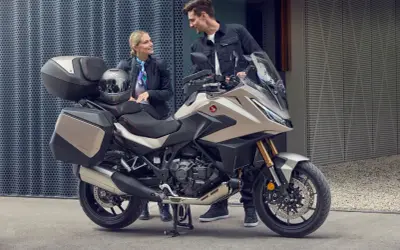 Pareja sonriente junto a una Honda NT 1100, lista para viajar. Opiniones positivas sobre su comodidad y diseño.