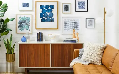 A stylish gallery wall features abstract blue art, geometric prints, and a framed textile.