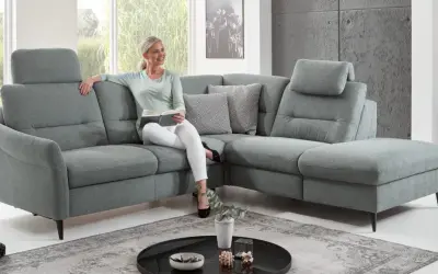 Frau liest auf einem gemütlichen Ecksofa mit verstellbaren Kopfstützen. Die tiefe **sitztiefe sofa** lädt zum Entspannen ein.