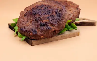 Dwa soczyste kotlety na desce, idealne do burgera. Dowiedz się, jak smażyć burgera, by były tak pyszne!