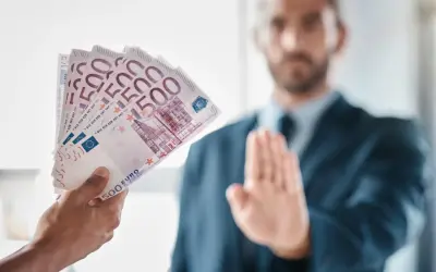 Ręka podaje plik banknotów 500 euro, mężczyzna w garniturze odrzuca je, co może symbolizować pozew o zapłatę.