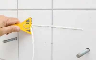 Main jaune en action pour enlever silicone vinaigre. Le joint est retiré proprement.
