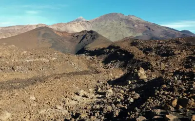Paisaje volcánico árido visto desde el mirador de Samara, con montañas y conos de ceniza bajo un cielo azul.
