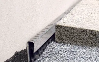 Noppenbahn mit Bitumen kleben: Detailaufnahme einer Fassadenabdichtung mit Drainageschicht und Granitstufe.