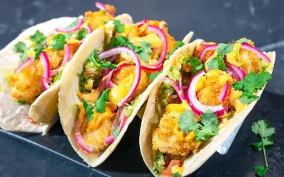 Friterade fisktacos med krämig sås, rödlök och färsk koriander. En härlig mango salsa skulle passa perfekt till!