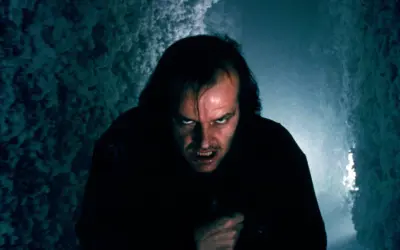 Jack Nicholson z przerażającą miną w ciemnym korytarzu.