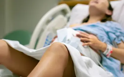Kobieta w szpitalnym łóżku, przygotowująca się do porodu. Czeka na nią "koktajl położnej", który pomoże jej w tym ważnym momencie.