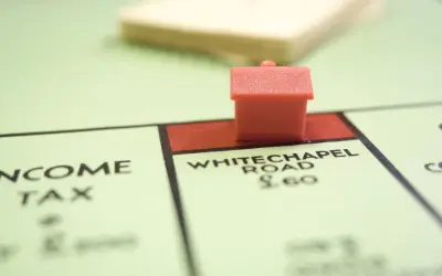Une petite maison rouge sur le plateau Monopoly, près de Whitechapel Road. Le jeu simule le transfert de prêt.
