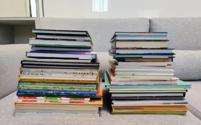 Dwie wysokie sterty książek na kanapie. Zastanawiasz się, czy można oddać swoje książki do biblioteki?