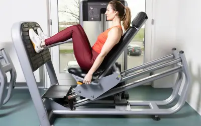 Kvinna tränar benpress rumpa på gym.