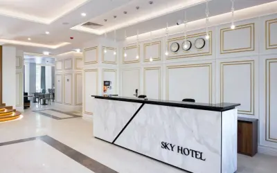 Eleganckie lobby hotelu Sky Kraków z marmurowym recepcjonistą i zegarami światowymi.