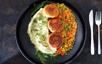 Kotleciki z puree ziemniaczanym i kolorową marchewką z groszkiem, udekorowane koperkiem. Pyszny, domowy obiad.